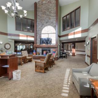 A spacious lobby featuring a central fireplace with comfortable seating and large windows.