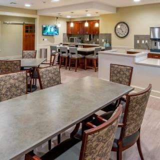 A modern meeting room with a conference table and adjacent kitchen area.