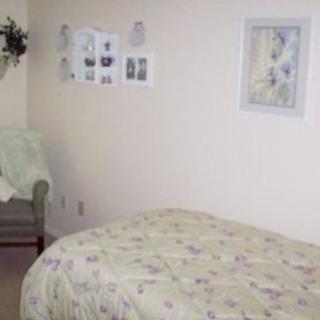 A cozy bedroom with a neatly made bed, an armchair, and wall decorations.