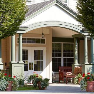 A welcoming porch with plants and outdoor seating at the entrance of a building.