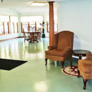 A bright indoor lounge area with comfortable chairs and a table near large windows.
