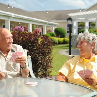 An elderly couple enjoying a game of cards in a sunny garden.