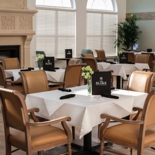 An elegant dining room with neatly set tables and chairs, featuring white tablecloths and a cozy ambiance.