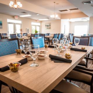 A modern restaurant dining room with neatly set tables, featuring glasses and napkins.
