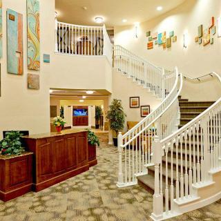 A spacious lobby with a grand staircase and decorative artwork on the walls.