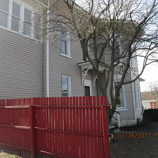A residential house with a red fence and bare tree in the yard.