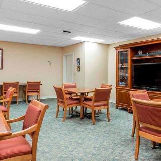 A spacious room with tables and chairs, featuring a television and warm lighting.