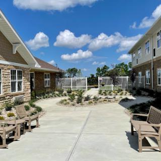 A bright courtyard surrounded by residential buildings, featuring landscaped areas and comfortable seating.