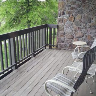 A scenic balcony with chairs overlooking a lush green view.
