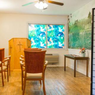 A small room with chairs arranged in front of a wooden pulpit, featuring a vibrant window and decorative elements.