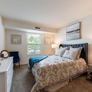 A cozy bedroom with elegant decor and a large window letting in natural light.