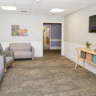 A modern waiting room with comfortable seating, a television, and decorative artwork.