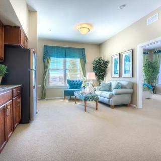 A cozy living room with a sofa, large window, and kitchenette area.