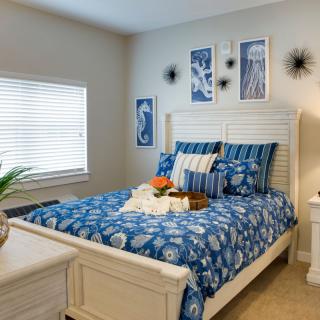 A cozy bedroom featuring blue and white decor with a neatly made bed and stylish artwork on the walls.