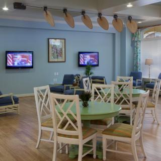 A cozy lounge area with tables, chairs, and televisions mounted on the wall.