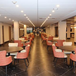 A spacious restaurant interior with neatly arranged tables and chairs, well-lit with overhead lighting.