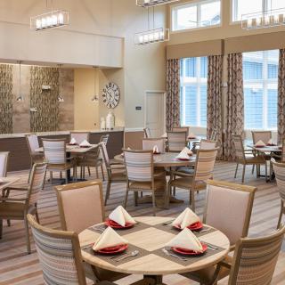 A well-lit dining area featuring neatly arranged tables with chairs and red napkins.
