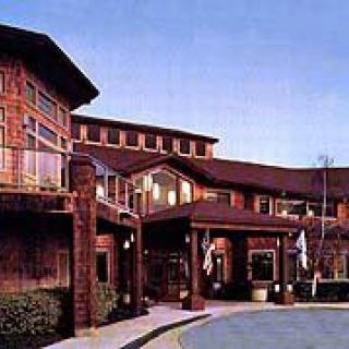 An exterior view of a hotel or resort building in the evening with illuminated lights.