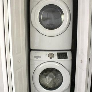 A stacked washer and dryer unit in a narrow closet space.