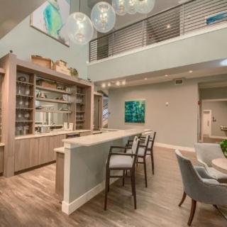 A modern living space featuring a bar area with counter seating and elegant chandeliers.