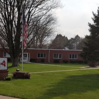 A serene view of a brick building with an American flag and well-maintained lawn.