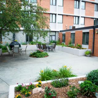 A serene courtyard with patio seating and well-maintained garden beds in an urban setting.