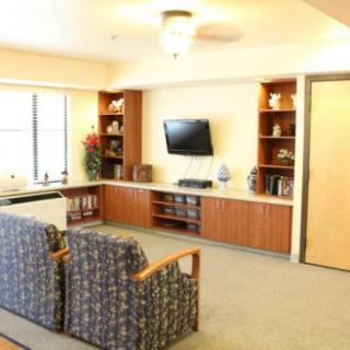 A modern living room with a television, shelves, and comfortable seating.