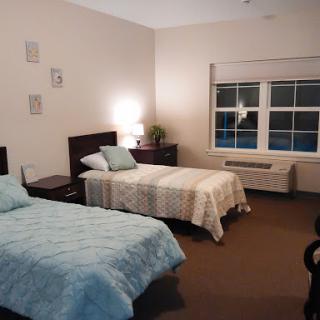 A cozy bedroom featuring two beds, soft lighting, and a calming color palette.