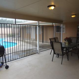 Covered patio with outdoor furniture, a grill, and fenced pool area.