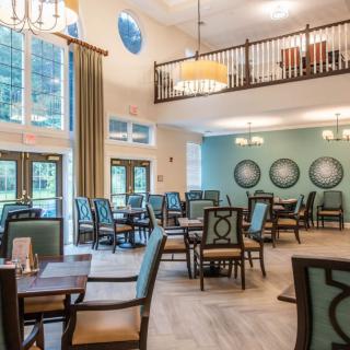 A spacious dining room featuring elegant chandeliers, large windows, and neatly arranged tables and chairs.