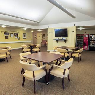 A cozy dining area with multiple tables and chairs, featuring a television and vending machine.