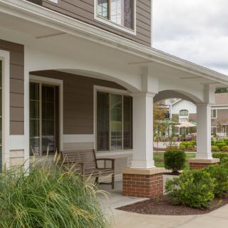 A charming suburban house with a spacious front porch and well-maintained garden.