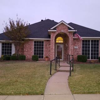 A brick house with a front lawn and an American flag displayed near the entrance.
