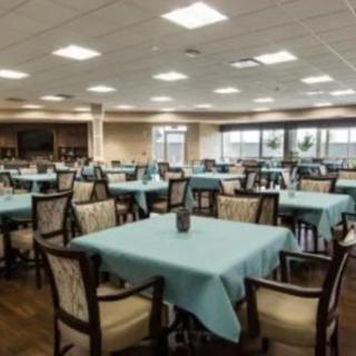 A spacious dining area with neatly arranged tables and chairs, covered in light blue tablecloths.