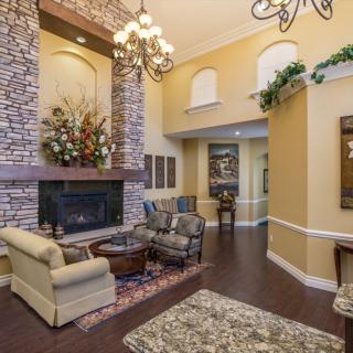 A cozy living room featuring a stone fireplace, elegant chandelier, and comfortable seating.