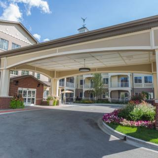 A welcoming hotel entrance with neatly maintained landscaping and a covered driveway.