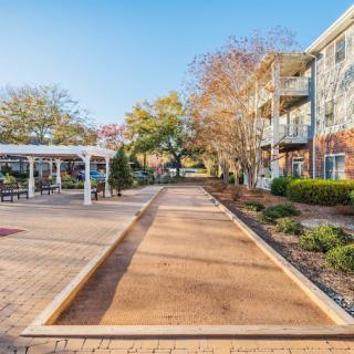 An outdoor walkway featuring a bocce court and landscaped gardens in a residential area.
