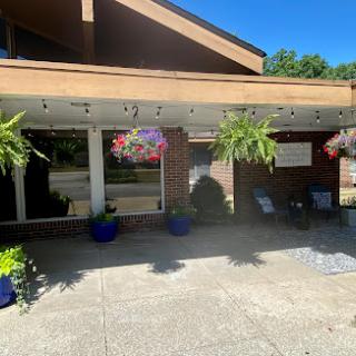A bright and welcoming entrance to a building, adorned with vibrant hanging plants and colorful planters.