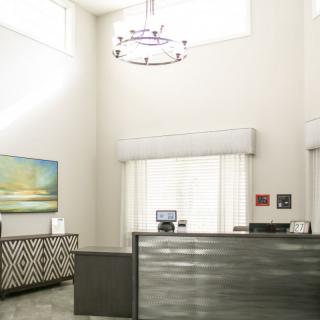 A modern reception area with a front desk, wall art, and a stylish chandelier.