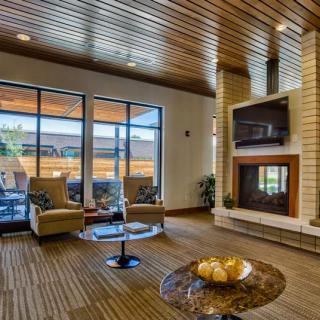 A modern living room with a wooden ceiling, featuring a fireplace and large glass doors leading to the outside.