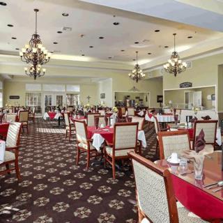 An elegant dining room with red tablecloths and ornate chandeliers.