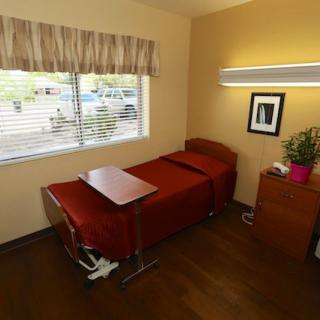 A hospital room with a single bed, side table, and window.