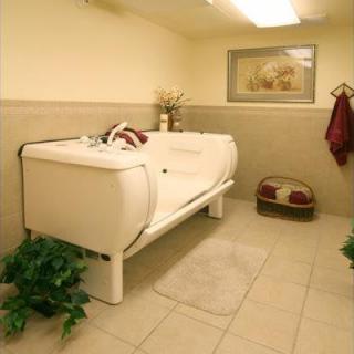 A spacious bathroom featuring a modern bathtub, decorative plants, and a neatly arranged towel rack.