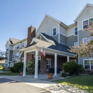 A residential building with a covered entrance, featuring landscaped surroundings and an American flag.