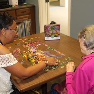 Two women working on a jigsaw puzzle together at a table.