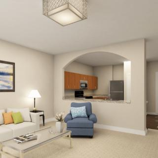A modern living room with a cozy armchair, sofa, and a view into the kitchen.