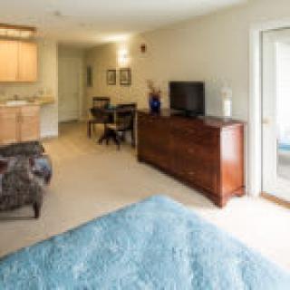 A modern bedroom interior featuring a dresser, television, and seating area.