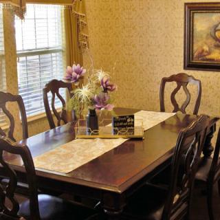 A cozy dining room featuring a wooden table set with chairs, adorned with a floral centerpiece and complemented by wall art.