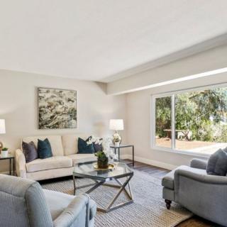 A bright and spacious living room with modern furniture and a large window overlooking greenery.
