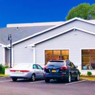 A small building with parked cars in front, seen during the daytime.